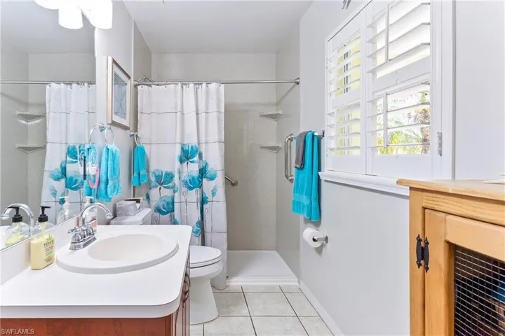 Full bathroom featuring vanity, tile patterned flooring, toilet, and curtained shower