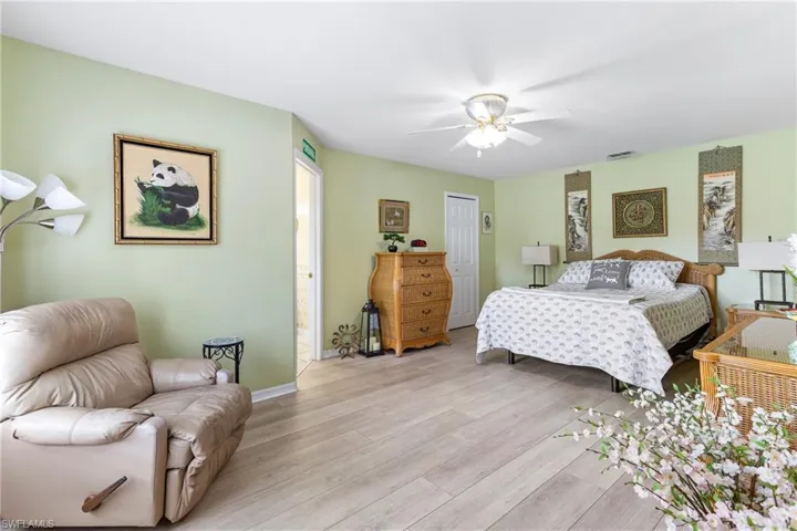 Bedroom featuring light wood-style floors, a ceiling fan, baseboards, and ensuite bath