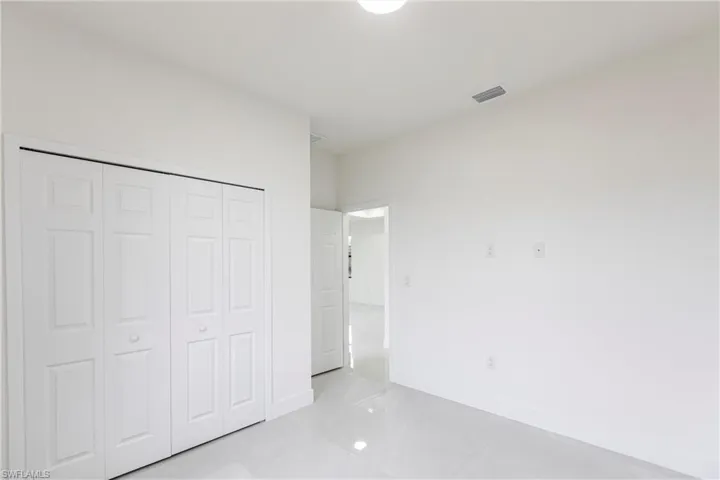 Unfurnished bedroom with a closet, visible vents, and baseboards