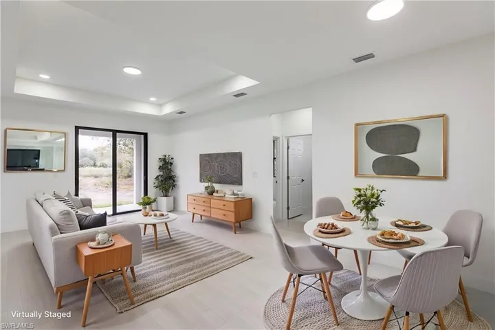 Living area featuring recessed lighting, visible vents, baseboards, light wood-type flooring, and a tray ceiling