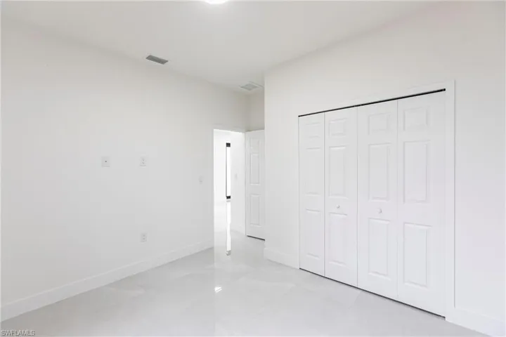 Unfurnished bedroom with baseboards, visible vents, and a closet
