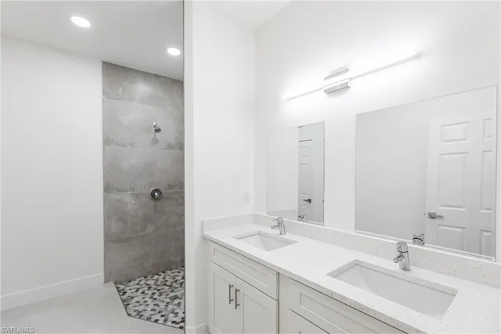 Full bathroom with recessed lighting, double vanity, a sink, and a walk in shower
