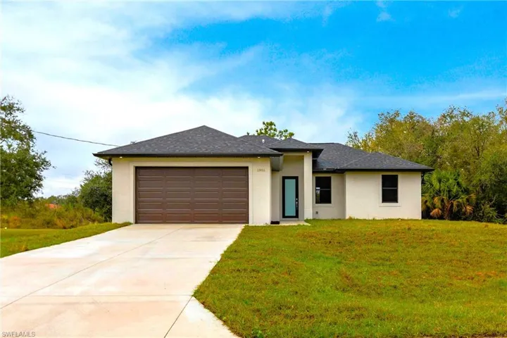 Prairie-style home featuring an attached garage, driveway, roof with shingles, stucco siding, and a front lawn