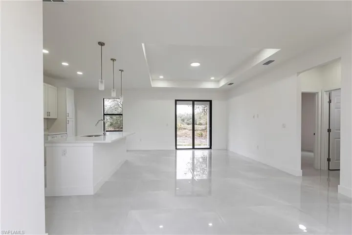 Unfurnished room featuring a tray ceiling, recessed lighting, a sink, and baseboards