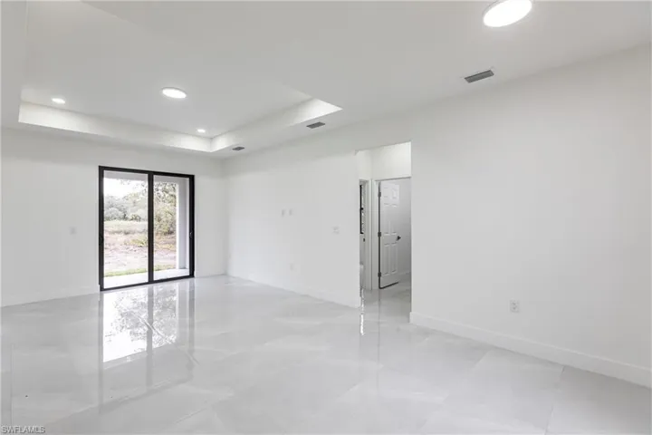 Empty room featuring visible vents, a tray ceiling, baseboards, and recessed lighting