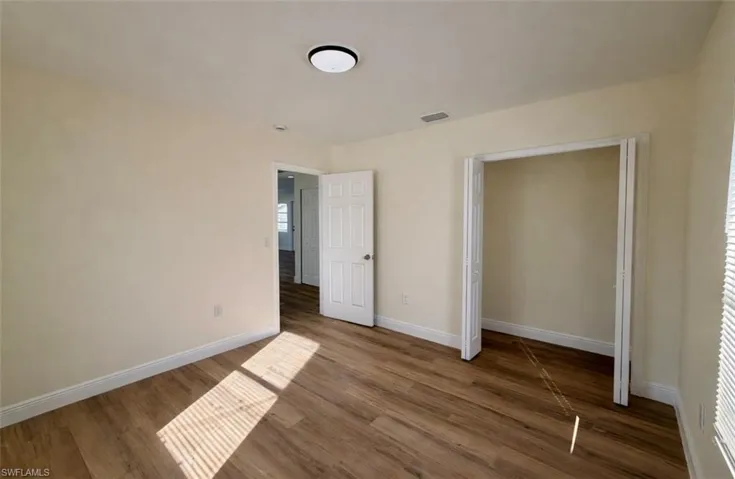 Unfurnished bedroom with wood finished floors and baseboards