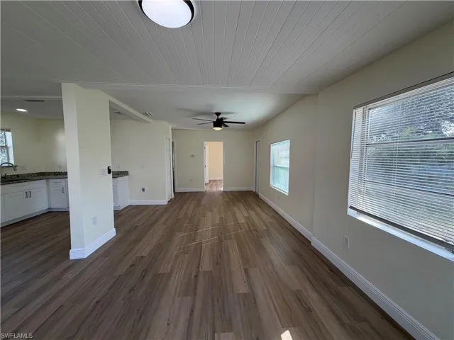 Unfurnished living room with dark wood finished floors, wood ceiling, and a ceiling fan