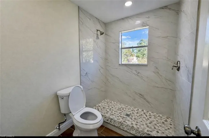 Bathroom with a marble finish shower and toilet