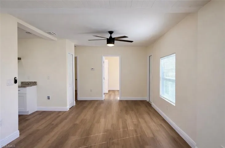Empty room featuring dark wood-type flooring, ceiling fan, and wooden ceiling