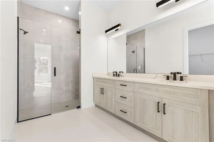 Master Full bath featuring a shower stall, double vanity, and finished concrete flooring