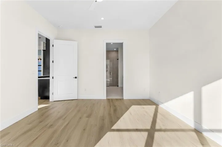 Master bedroom featuring light wood-style flooring, recessed lighting, ensuite bath, and a ceiling fan