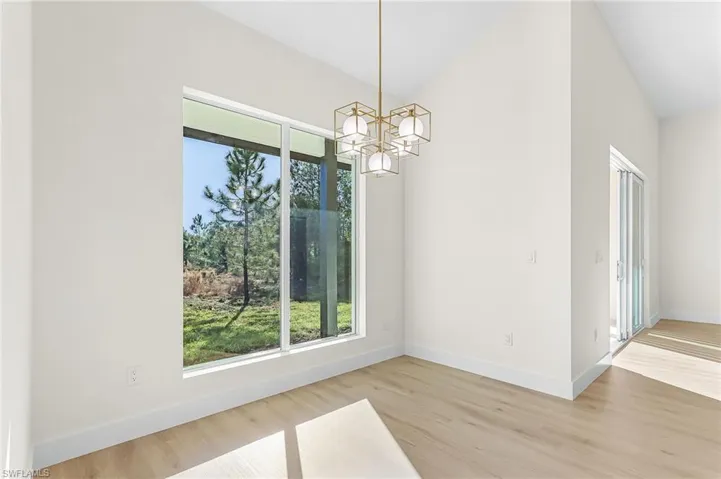 Dining area with suspended lighting, vaulted ceiling, and light wood-type flooring