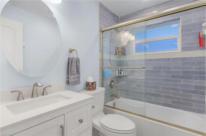 Full bathroom with shower / bath combination with glass door, vanity, and toilet