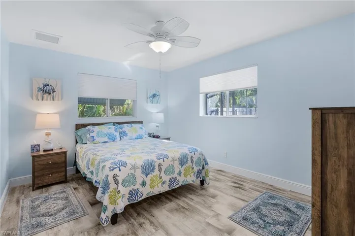Bedroom with light hardwood / wood-style flooring, multiple windows, and ceiling fan