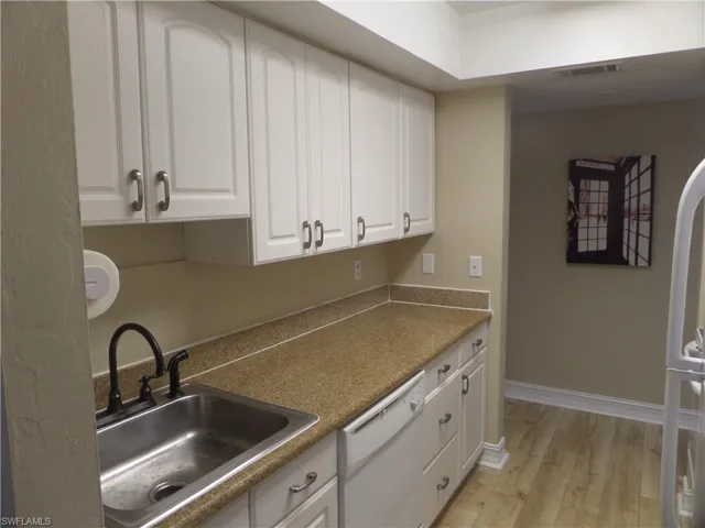 Kitchen with dishwasher, sink, white cabinets, and light hardwood / wood-style floors