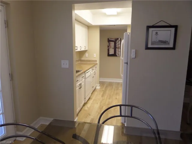 Kitchen with white dishwasher, light hardwood / wood-style flooring, and white cabinets