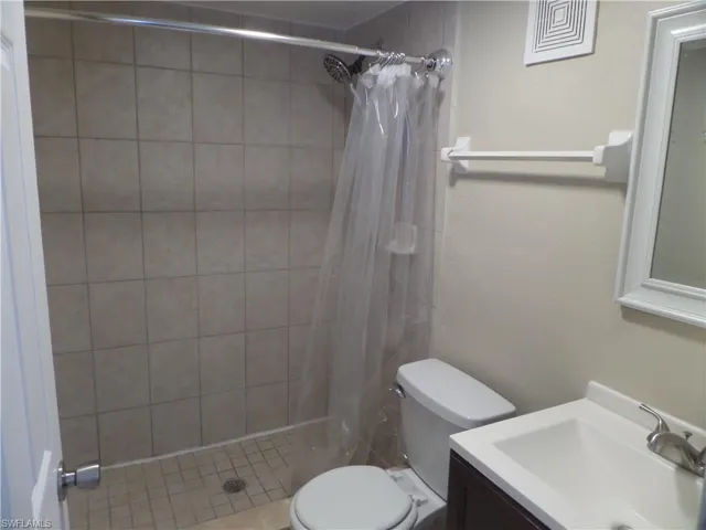 Bathroom featuring vanity, curtained shower, and toilet