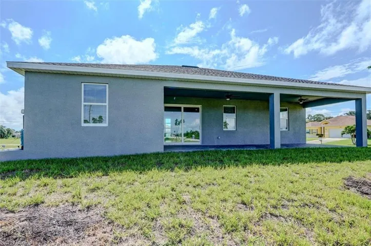 Back of house with a patio, ceiling fan, and a lawn