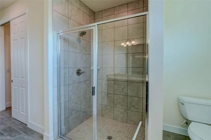 Bathroom featuring toilet, tile patterned floors, and walk in shower