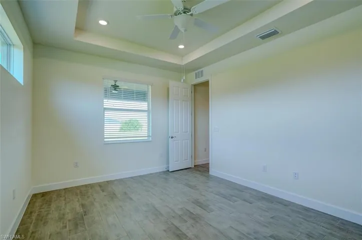 Empty room featuring hardwood / wood-style floors, ceiling fan, and a raised ceiling