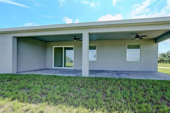 Rear view of property with a yard, ceiling fan, and a patio area