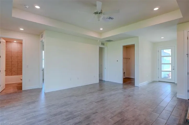 Unfurnished room with light wood-type flooring, ceiling fan, and a raised ceiling