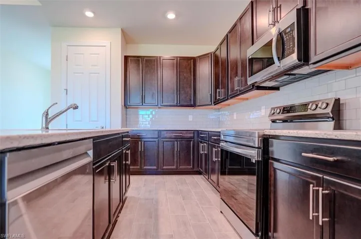 Kitchen featuring dark brown cabinetry, decorative backsplash, sink, and stainless steel appliances