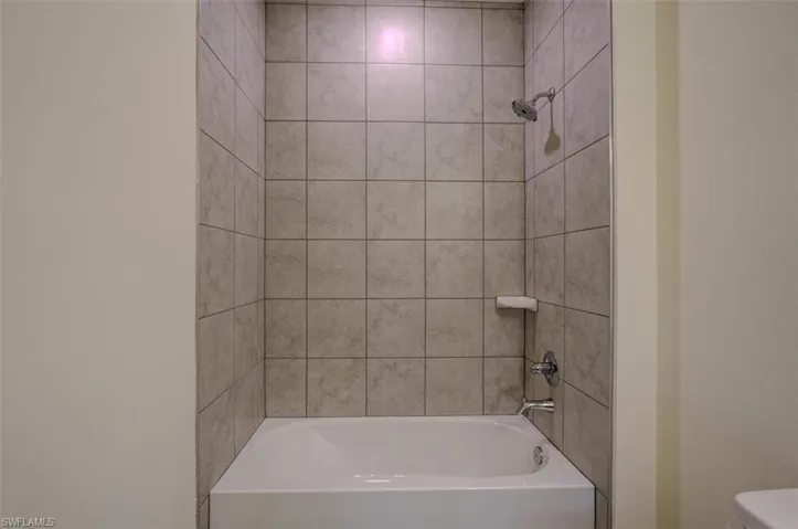Bathroom with tiled shower / bath and toilet