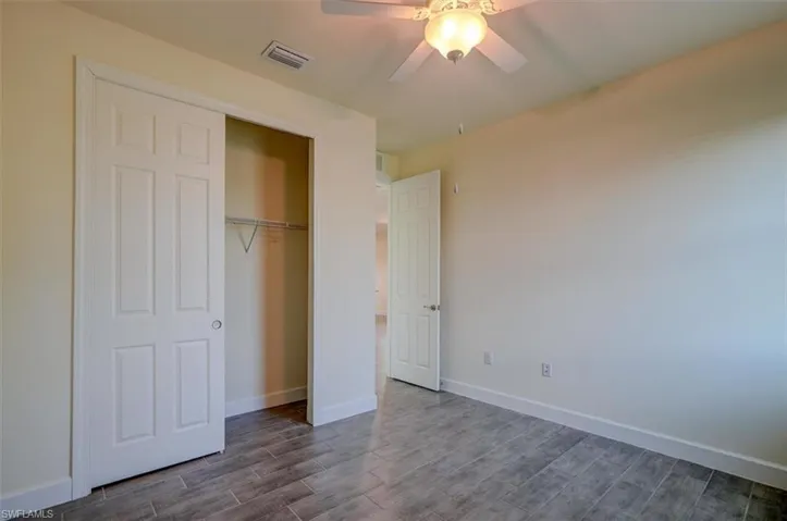 Unfurnished bedroom featuring dark hardwood / wood-style floors, a closet, and ceiling fan