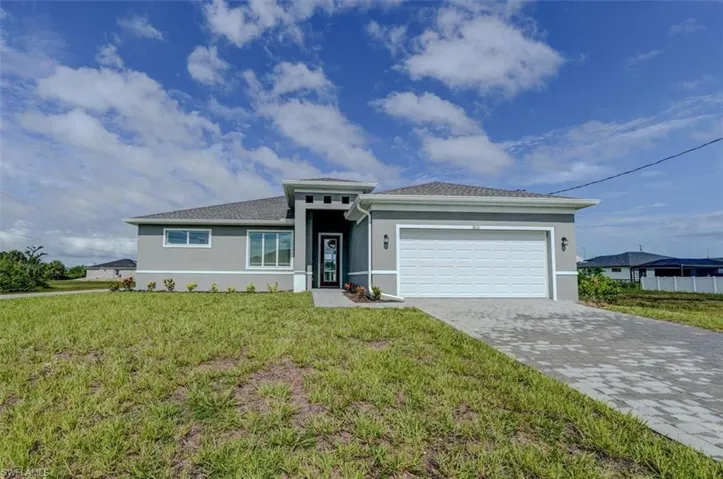 View of front facade featuring a garage and a front lawn