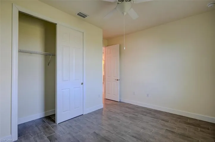 Unfurnished bedroom with dark hardwood / wood-style flooring, a closet, and ceiling fan