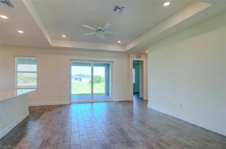 Spare room featuring hardwood / wood-style floors, ceiling fan, and a raised ceiling