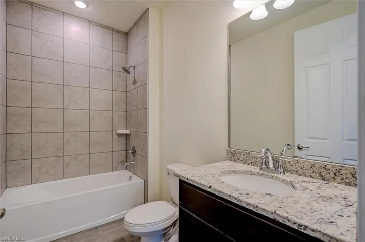 Full bathroom with toilet, vanity, and tiled shower / bath