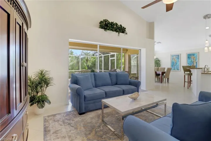 Living room with ceiling fan, high vaulted ceiling, and light tile patterned floors