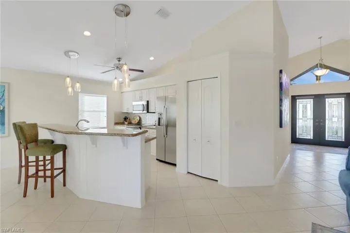 Kitchen with french doors, hanging light fixtures, appliances with stainless steel finishes, light stone countertops, and white cabinets