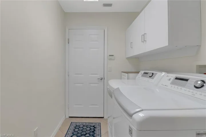 Laundry area with cabinets, washing machine and dryer, and light tile patterned floors