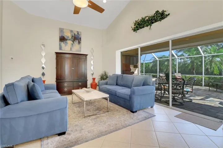 Living room with high vaulted ceiling, light tile patterned floors, and ceiling fan