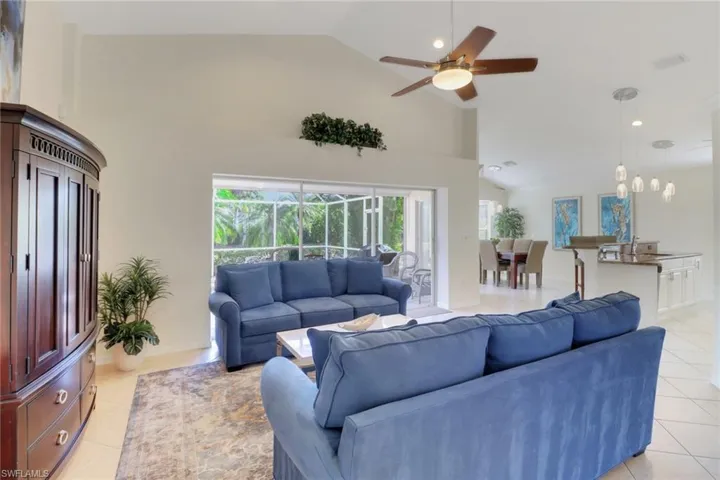 Living room with ceiling fan, sink, high vaulted ceiling, and light tile patterned floors