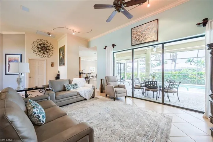 Living room featuring ceiling fan, ornamental molding, light tile flooring, and rail lighting
