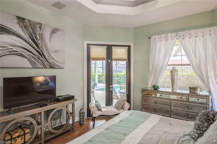 Bedroom with dark wood-type flooring, french doors, access to exterior, and multiple windows