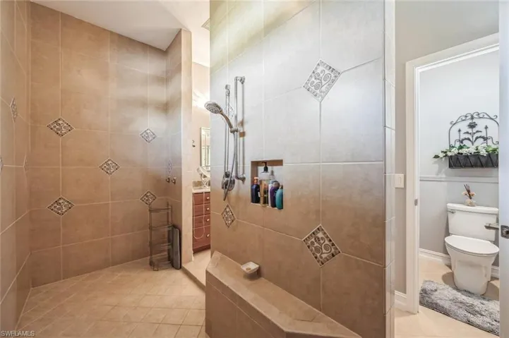 Bathroom with a tile shower, toilet, and tile floors