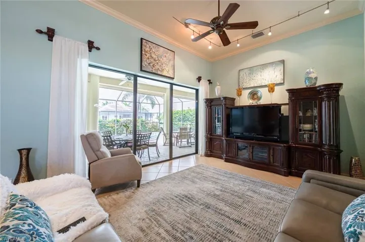 Living room featuring track lighting, ceiling fan, light tile floors, and crown molding