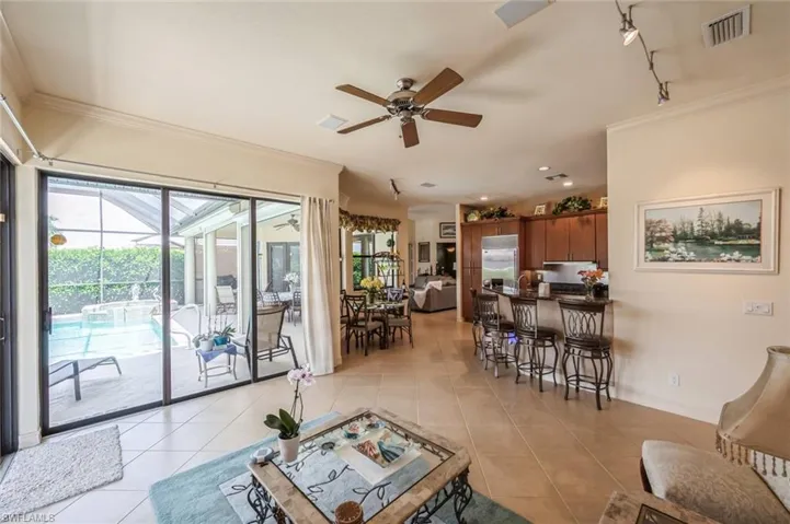 Tiled living room with crown molding, track lighting, and ceiling fan