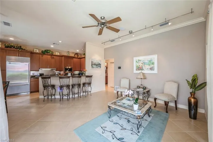 Living room featuring ceiling fan, crown molding, light tile flooring, and rail lighting