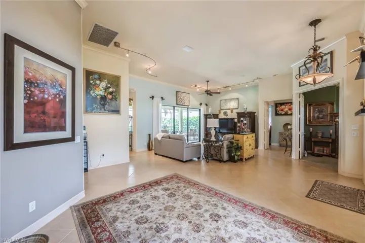 Living room with tile flooring, ceiling fan, rail lighting, and crown molding