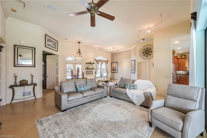 Living room featuring ceiling fan, tile flooring, crown molding, and rail lighting