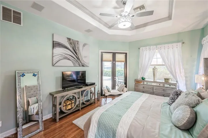 Bedroom with access to outside, ceiling fan, a tray ceiling, hardwood / wood-style floors, and french doors