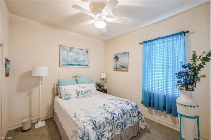 Carpeted bedroom featuring ceiling fan and multiple windows
