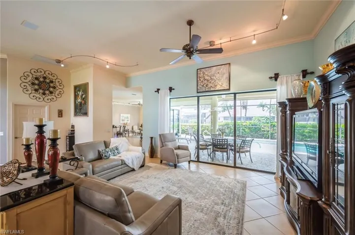 Tiled living room with ornamental molding, ceiling fan, and rail lighting