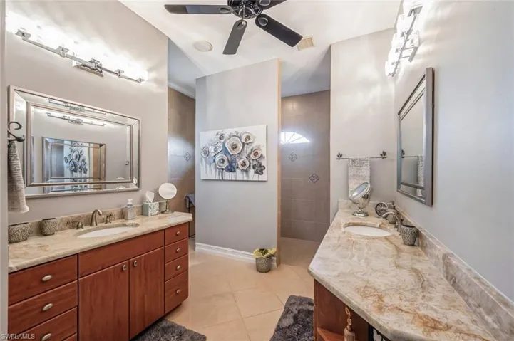 Bathroom featuring ceiling fan, tile flooring, and vanity with extensive cabinet space